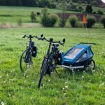 E-Bikes mit Anhänger, Gepäcktaschen und Helmen auf einer Wiese