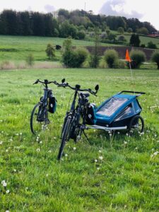 E-Bikes mit Anhänger, Gepäcktaschen und Helmen auf einer Wiese