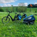 E-Bikes mit Anhänger, Gepäcktaschen und Helmen auf einer Wiese