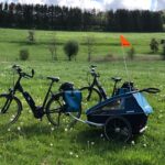 E-Bikes mit Anhänger, Gepäcktaschen und Helmen auf einer Wiese