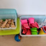 2 Kisten mit Topfstelzen, Hütchen, Holzeisenbahn, Bällen