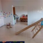 Blick in 2 Räume mit Schaukelpferd, Rutsch, Arbeitstischen, Speisehaus, Spielküche, Bällebad