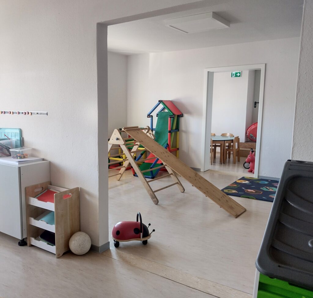 Blick auf Klettergerüst, Rutsche, Spielteppich, Fahrzeug